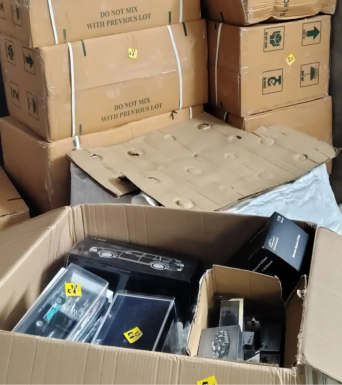 Stack of cardboard boxes with electronic equipment inside, on a concrete floor model car seller company